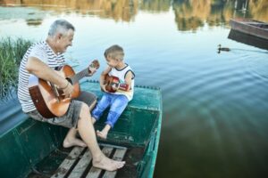 Grandfather showing his grandson to play the guitar