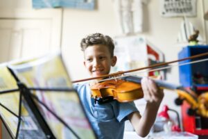 Little boy playing the violin while looking at sheet music