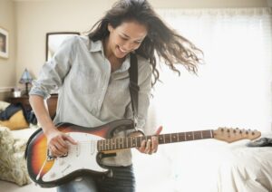 Young woman smiling and playing the electric guitar