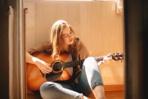 Young woman sitting on the floor playing an acoustic guitar
