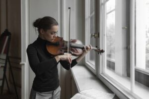 Woman playing the violin staring out the window