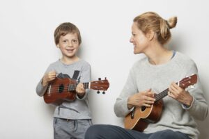 Mother and son wearing grey sweatshirts playing the ukulele