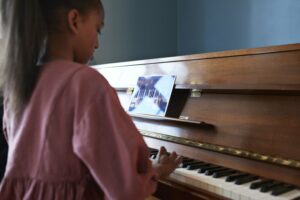 Little girl playing the piano using an online lesson
