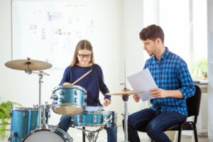 Male instructor showing a female student to play the drums