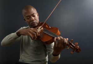 Man in a long sleeved shirt playing the violin
