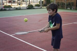 Little boy bouncing ball on a tennis racquet
