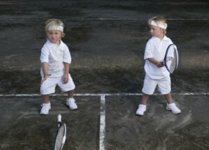 Two little boys holding tennis racquets