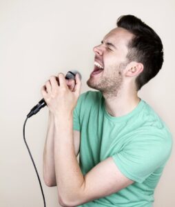 Man in blue shirt singing into microphone