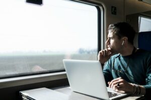 Man staring out the window while looking at his laptop