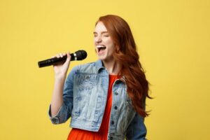 Red haired woman singing into a microphone