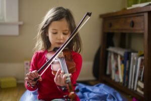 Young girl playing violin on the floor