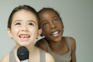 Little boy and little girl singing into a microphone