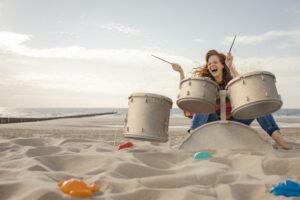 Woman playing sandy drums at beach