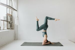 Woman in an empty white room doing inverted yoga