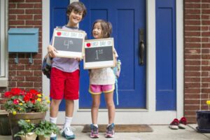 Brother and sister holding up first day of school chalk boards before school