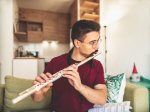 Young man wearing glasses playing the flute