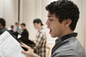 Young man reading music and singing in a choir