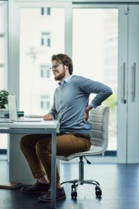 Man sitting at his desk holding his hurting back