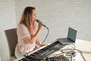 Young woman singing into a microphone connected to her laptop