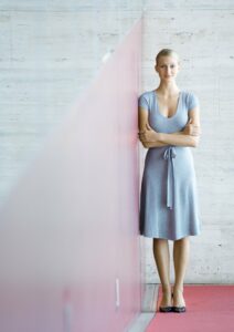 Business woman standing up straight against a wall