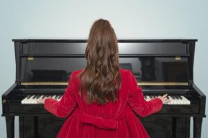Back view of a young woman playing the piano