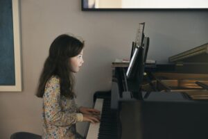 Little girl playing the piano with an online lesson
