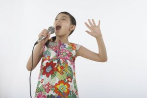 Little girl in a dress singing into a microphone 