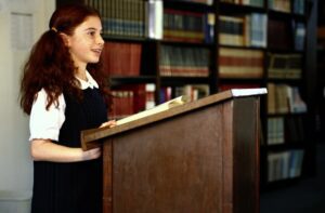 Little girl with pigtails standing at a podium