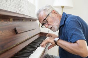 Older man wearing glasses playing the piano
