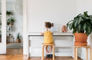 Little girl in pigtails sitting on a stool playing the piano