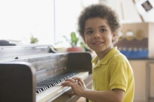 Little boy in a yellow polo sitting at the piano