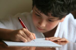 Close up of a little boy writing on a piece of paper