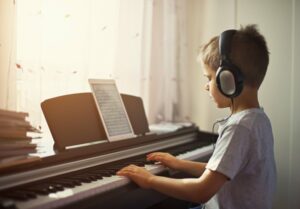 Little boy wearing headphones while playing the piano