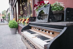 Picture of an old piano on the street outside of a shop