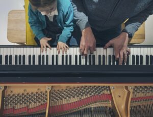 Father and daughter playing piano side by side