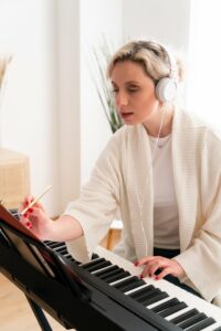 Young woman in a white sweater writing music at her keyboard