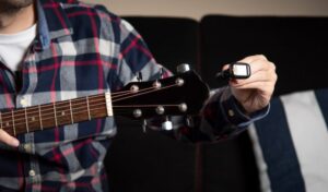 Closeup of a man using a digital tuner for his guitar