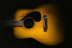 Close up of an old acoustic guitar against a black background