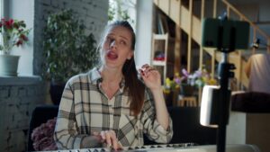 Young woman in a flannel shirt giving a singing lesson online