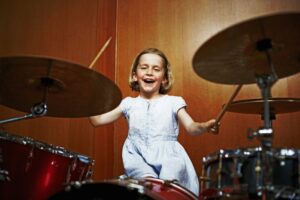 Little girl in a blue dress playing the drums