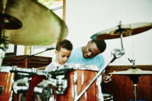 Man showing boy how to play drums