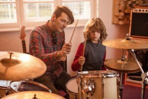Man teaching little boy to play drums