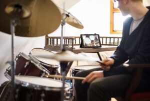Teen boy learning to play drums with help of online class