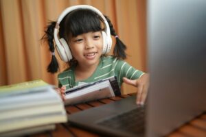 Little girl wearing headphones while learning online