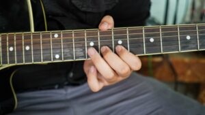 Close up of a man's fingers on a guitar neck