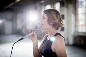 Female singer with short hair singing into a microphone 