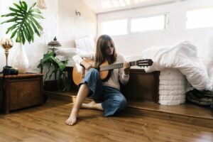Woman playing guitar on the floor in her room