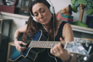 Woman playing guitar with headphones on