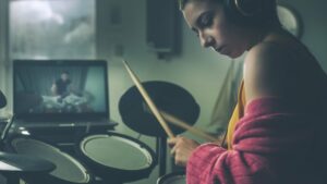 Young woman playing the drums with an online lesson