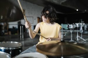 Little boy in a yellow shirt playing the drums